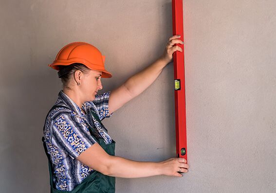 pintora com régua verificando alinhamento de parede para formular orçamento de pintura