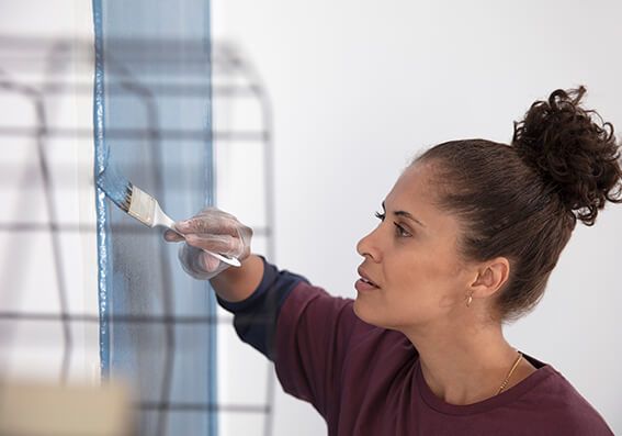 mulher pintando a parede depois de descobrir como diluir tinta