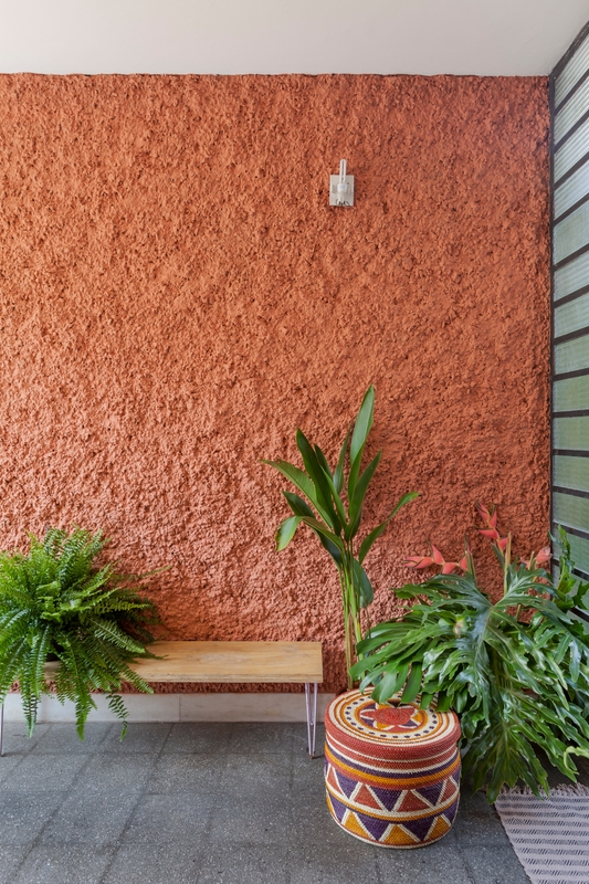 Área externa com parede Terracota Suvinil | Decoração com muitas plantas e piso cinza | Foto de Alessandro Guimarães