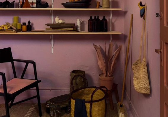 dispensa com cadeira de metal e prateleiras de madeira com parede rosa