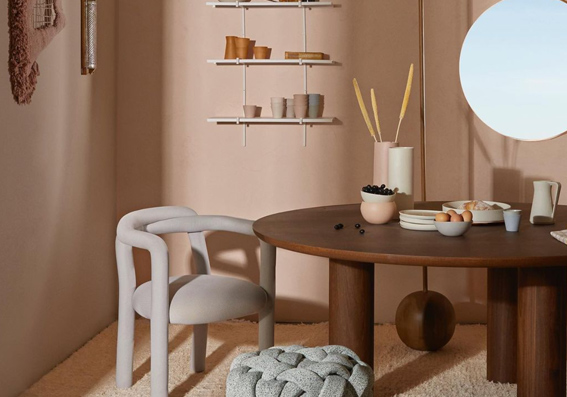atelie com mesa e puff cinza, mesa em madeira marrom e paredes rosa