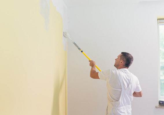 homem aplicando tinta branca em parede com rolo representando a dúvida: pintei a parede e choveu, e agora? 
