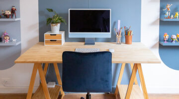 escritório com parede branca e pintura geométrica azul com mesa de madeira e cadeira azul representando cores de tinta semibrilho