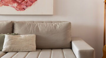 sofá bege em frente a parede clara representando qual a melhor tinta lávavel para parede interna