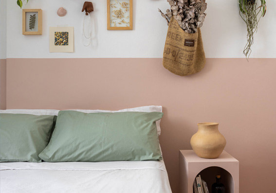 cama com lençol branco e almofadas verde com parede bicolor branca e rosa representando qual a melhor tinta lávavel para parede interna