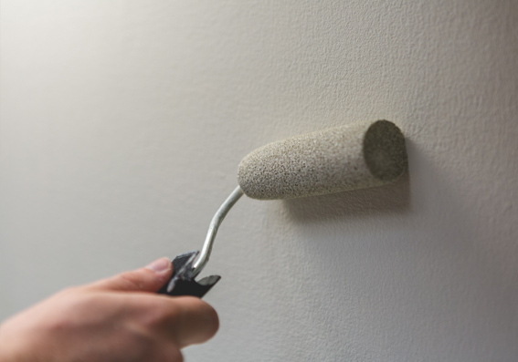 pessoa aplicando tinta cinza em parede com rolo