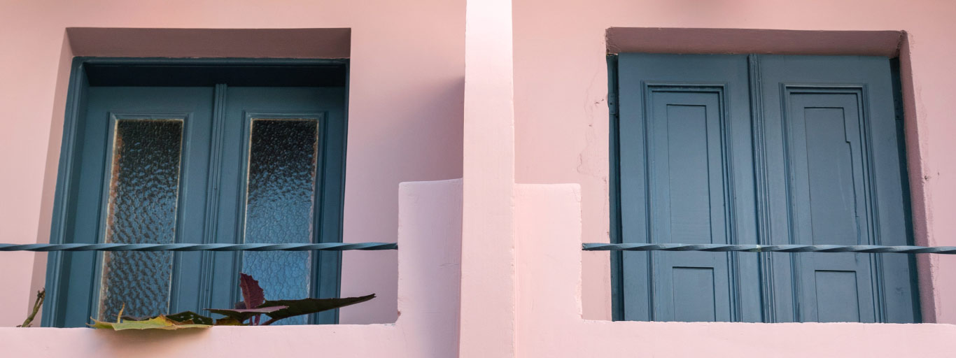 Imagem de um imóvel rosa com janelas azuis