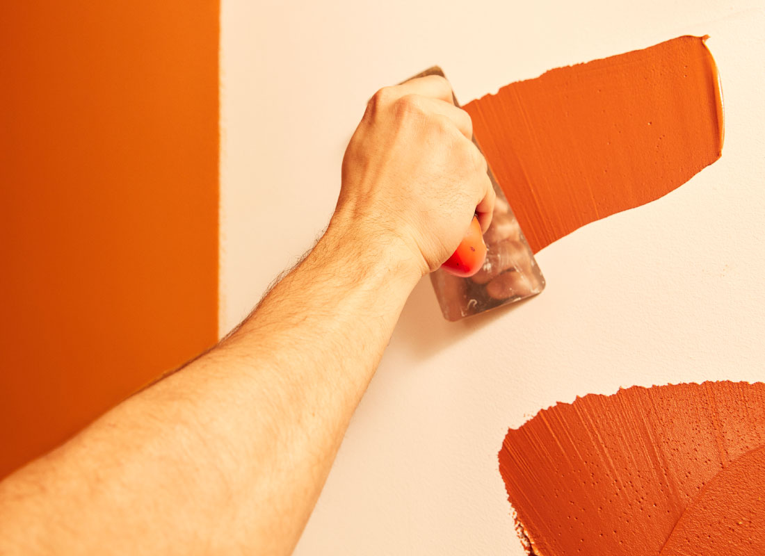 pessoa aplicando tinta com trincha na parede representando valor de tinta de parede