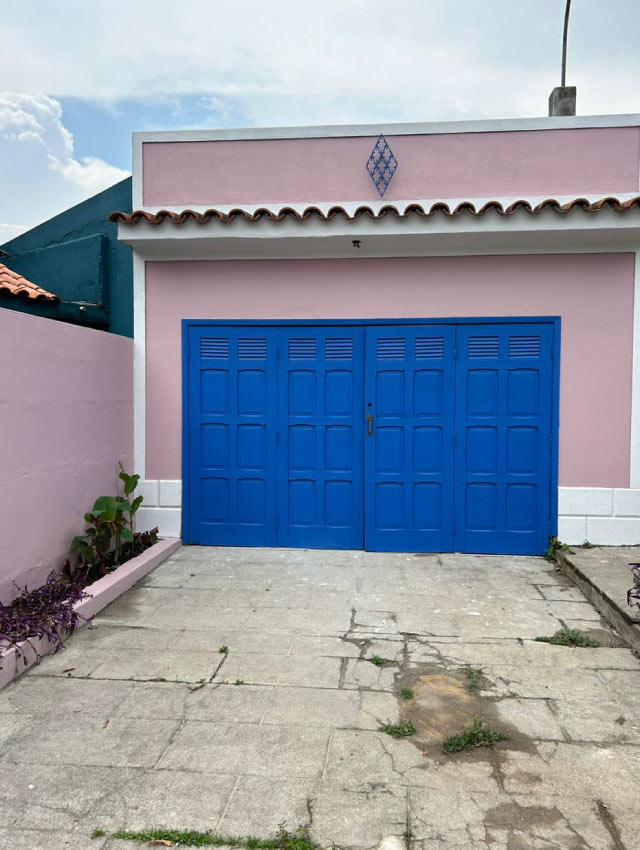 Imagem de casa rosa com portão azul