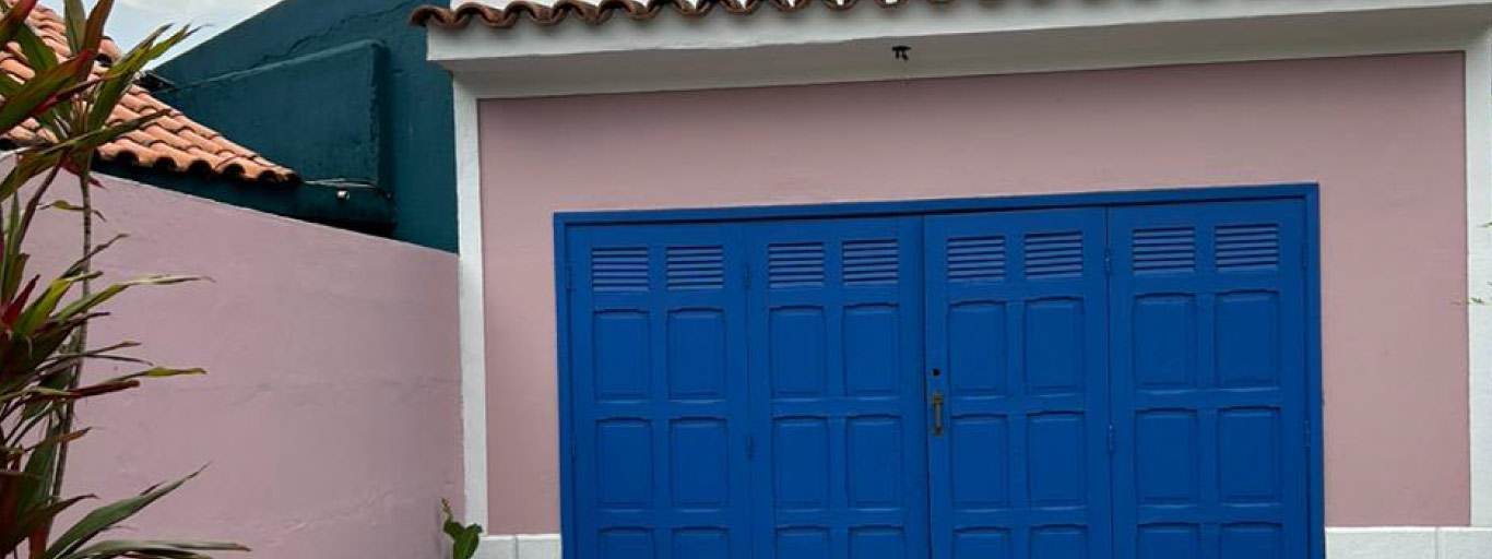 Imagem de casa pintada de rosa e com portão azul